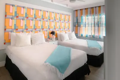 two beds in a room with colorful windows at The Cove By Renzzi in Miami Beach