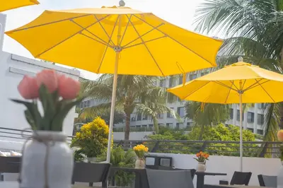 two yellow umbrellas on a patio with tables and chairs at The Cove By Renzzi in Miami Beach