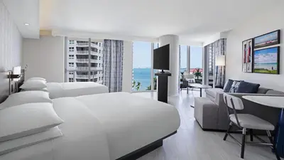 a white bedroom with a white bed and a living room at Hyatt Centric Brickell Miami in Miami