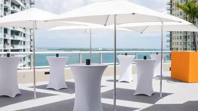 a row of white tables with umbrellas on a balcony at Hyatt Centric Brickell Miami in Miami