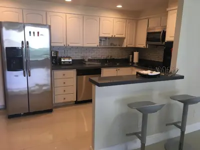 a kitchen with white cabinets and a stainless steel refrigerator at Ocean Reserve Piso 4 STR264 in Miami Beach