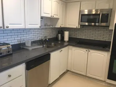 a kitchen with white cabinets and a sink and a microwave at Ocean Reserve Piso 4 STR264 in Miami Beach