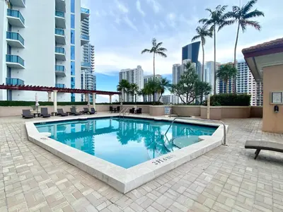 a swimming pool with palm trees and a building at The King David Condos in Miami Beach