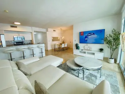 a living room with a white couch and a kitchen at The King David Condos in Miami Beach