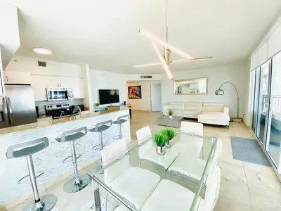 a kitchen and living room with a glass table at The King David Condos in Miami Beach