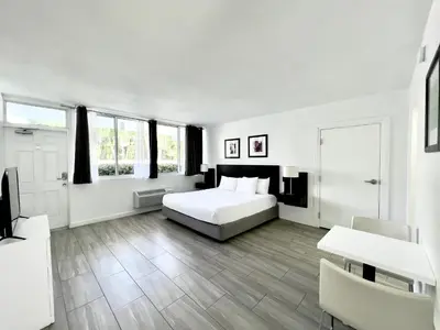 a white bedroom with a bed and a table and chairs at Beach Gardens in Fort Lauderdale