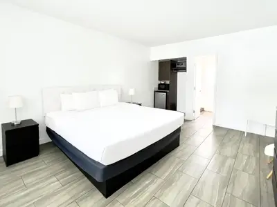 a white bedroom with a large bed and a kitchen at Beach Gardens in Fort Lauderdale