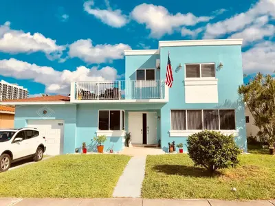 a blue house with a white car parked in front of it at Blue House Miami in Miami Beach