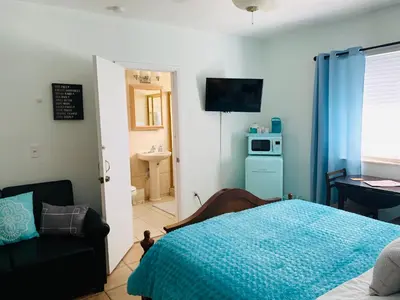 a bedroom with a bed and a chair and a microwave at Blue House Miami in Miami Beach
