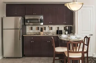 a kitchen with brown cabinets and a stainless steel refrigerator at Hilton Grand Vacations Club Mcalpin Ocean Plaza Miami in Miami Beach