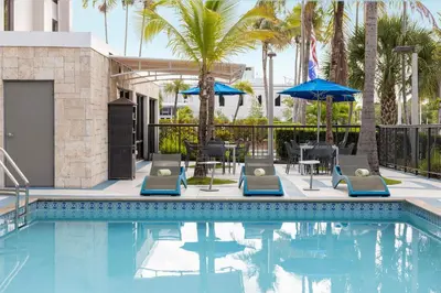 a pool at a hotel with chairs and umbrellas at Hampton Inn Miami-Airport West in Miami