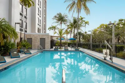 a swimming pool at a hotel with palm trees at Hampton Inn Miami-Airport West in Miami