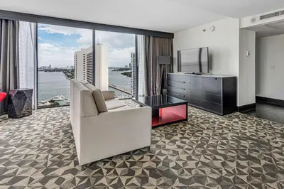 a living room with a couch and a tv and a large window at Hilton Miami Downtown in Miami