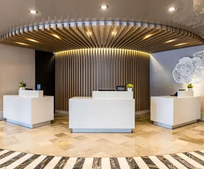 a lobby with white counters and a wooden wall at Hilton Bentley Miami South Beach in Miami Beach