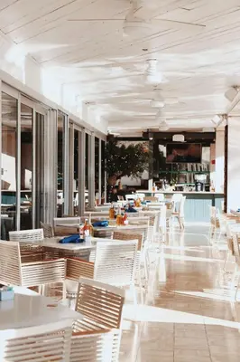 an empty restaurant with white tables and chairs at Hilton Bentley Miami South Beach in Miami Beach