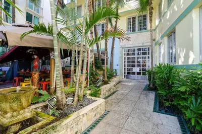 a courtyard with palm trees and a building with a restaurant at Ocean Drive Studio Historic Building minutes walk to the Beach. in Miami Beach