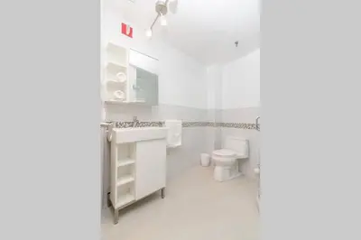 a white bathroom with a sink and a toilet at Ocean Drive Studio Historic Building minutes walk to the Beach. in Miami Beach