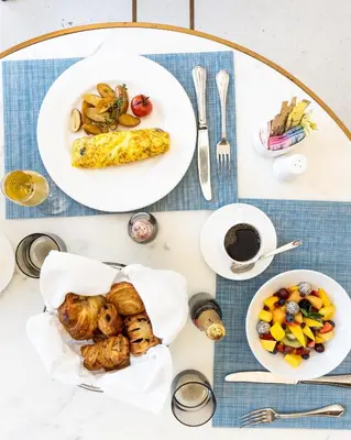 a table with two plates of food on it at The Dalmar, Fort Lauderdale, a Tribute Portfolio Hotel in Fort Lauderdale