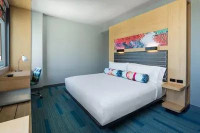 a bedroom with a white bed with a wooden headboard at Aloft Miami Aventura in Aventura