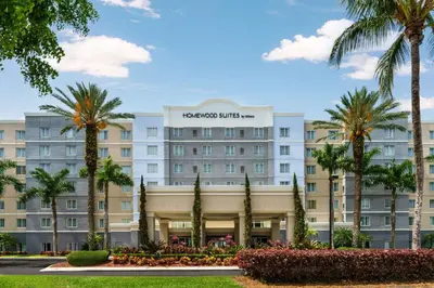 a hotel with palm trees in front of it at Homewood Suites Miami Airport/Blue Lagoon in Miami