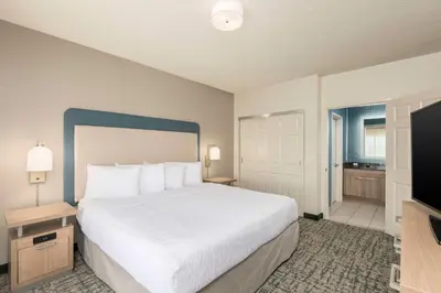 a bedroom with a large bed and a flat screen tv at Homewood Suites Miami Airport/Blue Lagoon in Miami