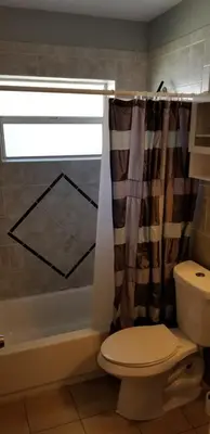 a bathroom with a toilet and a shower curtain at INN LEATHER GUEST HOUSE-GAY MALE ONLY in Fort Lauderdale
