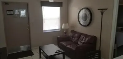 a living room with a couch and a clock on the wall at INN LEATHER GUEST HOUSE-GAY MALE ONLY in Fort Lauderdale