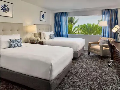 a hotel room with two beds and a chair at Sonesta Fort Lauderdale Beach in Fort Lauderdale