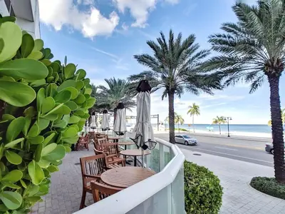 a balcony with tables and umbrellas and the beach at 1201 W Residences in Fort Lauderdale