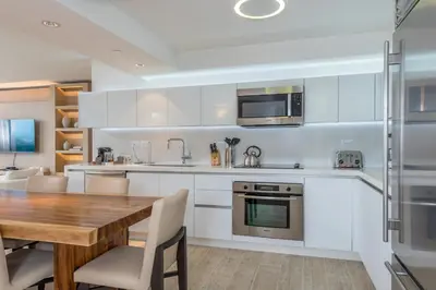 a kitchen with white cabinets and a wooden table at Oceanview Private Condo at 1 Hotel & Homes -915 in Miami Beach