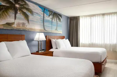 a hotel room with two beds and a palm tree mural at enVision Hotel Miami International Airport in Miami