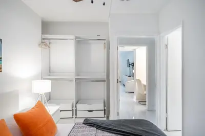 a bedroom with white walls and a bed with an orange pillow at Sunny Isles Ocean Reserve Superb Condo Apartments in Miami Beach