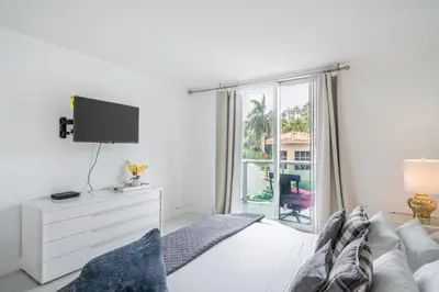 a white bedroom with a bed and a tv at Sunny Isles Ocean Reserve Superb Condo Apartments in Miami Beach