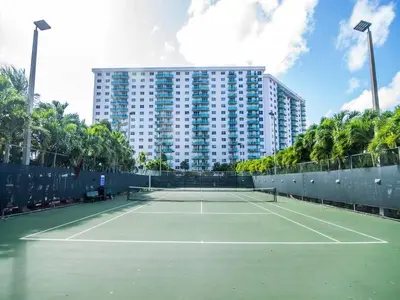 a tennis court in front of a large building at Sunny Isles Ocean Reserve Superb Condo Apartments in Miami Beach