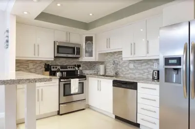 a kitchen with white cabinets and stainless steel appliances at Sunny Isles Ocean Reserve Condo Apartments in Miami Beach