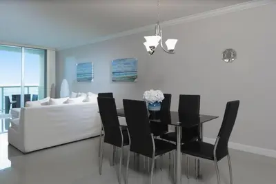 a dining room with a table and black chairs at Sunny Isles Ocean Reserve Condo Apartments in Miami Beach