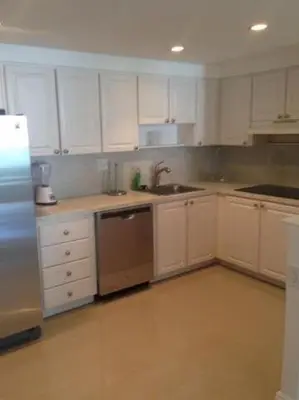 a kitchen with white cabinets and a stainless steel refrigerator at Sunny Isles Ocean Reserve Condo Apartments in Miami Beach
