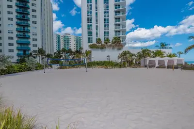 a large white beach with tall buildings in the background at 2 Bedroom on 17th floor on the beach Resort in Hallandale Beach