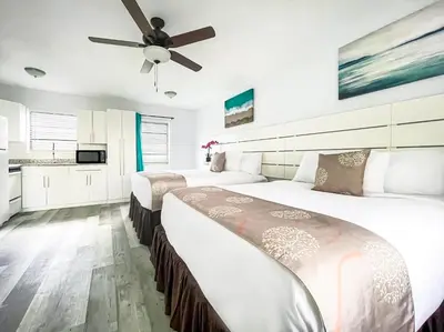 two beds in a hotel room with a ceiling fan at Silver Spray Motel in Hollywood