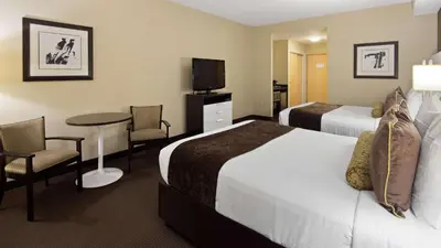a hotel room with two beds and a table and chairs at Best Western Plus Miami Intl Airport Hotel & Suites Coral Gables in Miami