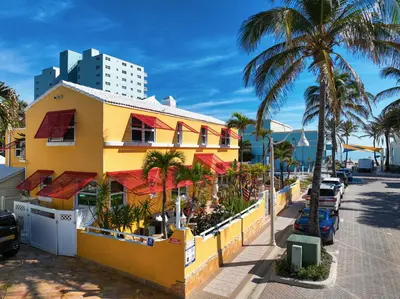 a yellow building next to a street with palm trees at Sinclair Boutique Hotel in Hollywood