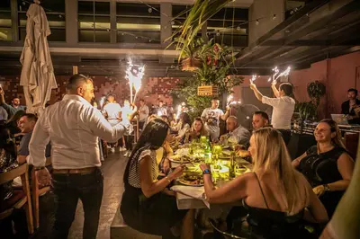 a group of people sitting around a table in a restaurant at Boulan South Beach in Miami Beach