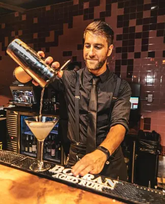 a man pouring a drink behind a bar at Boulan South Beach in Miami Beach