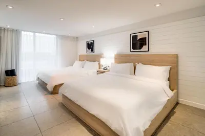 two beds in a hotel room with white sheets at Boulan South Beach in Miami Beach