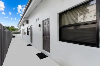 a white building with a pair of doors on it at Modern Loft wBed Steps from Beach Boardwalk in Hollywood