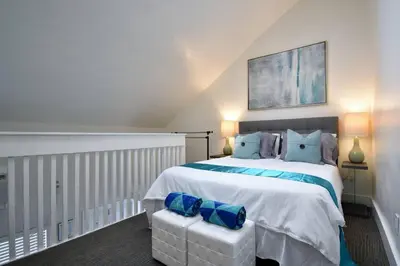 a bedroom with a large white bed with blue pillows at Modern loft wqueen bed steps to beach in Hollywood