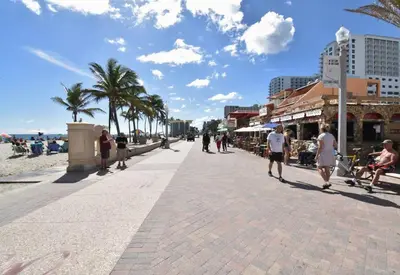 people walking on a sidewalk next to the beach at Modern loft wqueen bed steps to beach in Hollywood