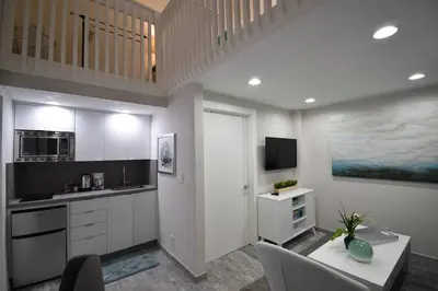 a kitchen with white cabinets and a table with chairs at Modern Loft wQueen Loft Steps to Beach in Hollywood