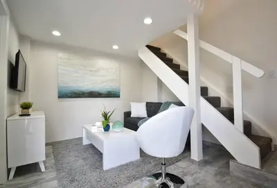 a living room with a white chair and stairs at Loft wqueen bed steps to Hollywood Beach in Hollywood