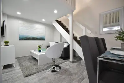 a white living room with a staircase and a chair at Loft wqueen bed steps to Hollywood Beach in Hollywood